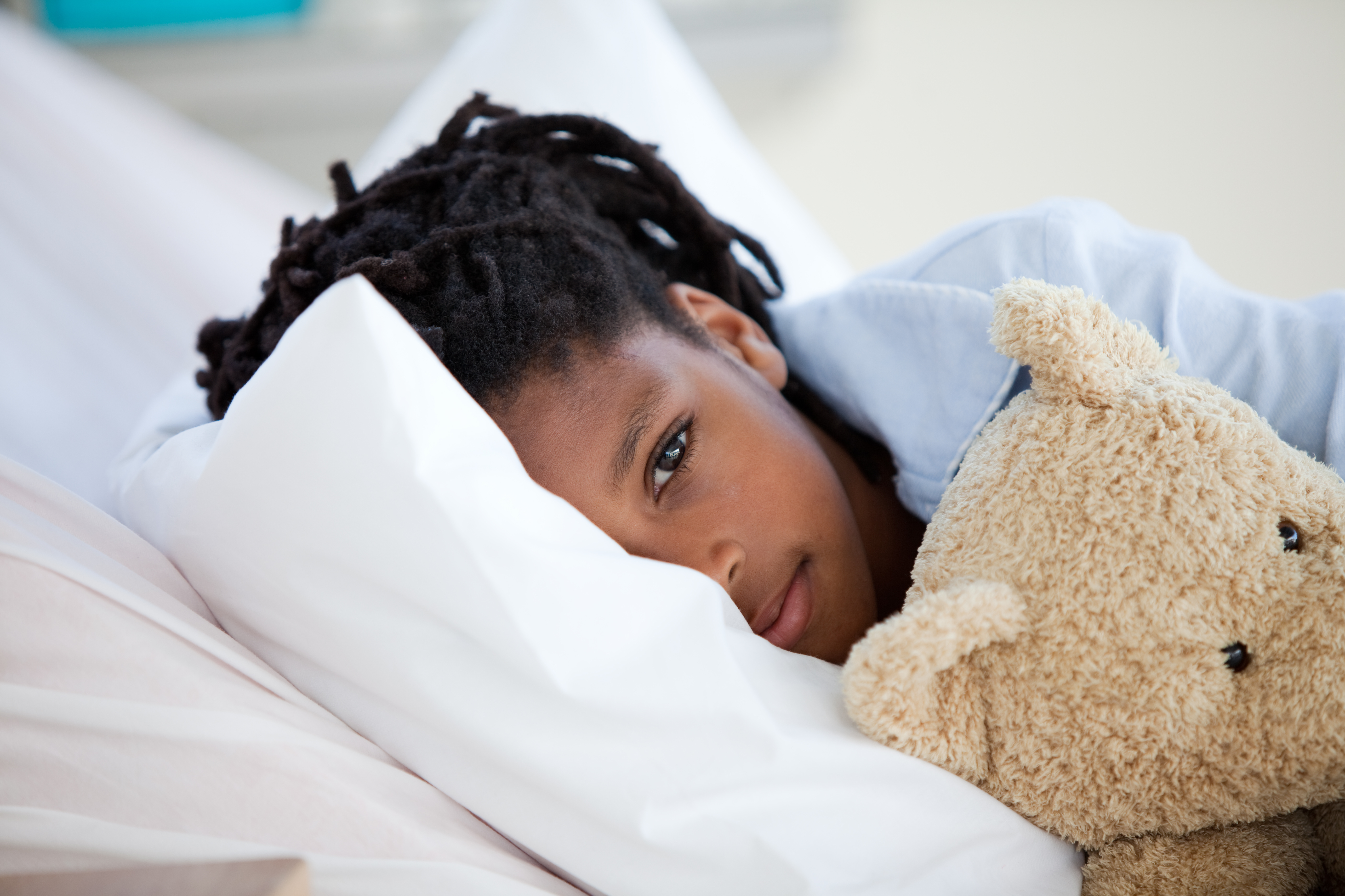sick girl laying in bed with teddy bear illness flu rsv covid viral rest sickness