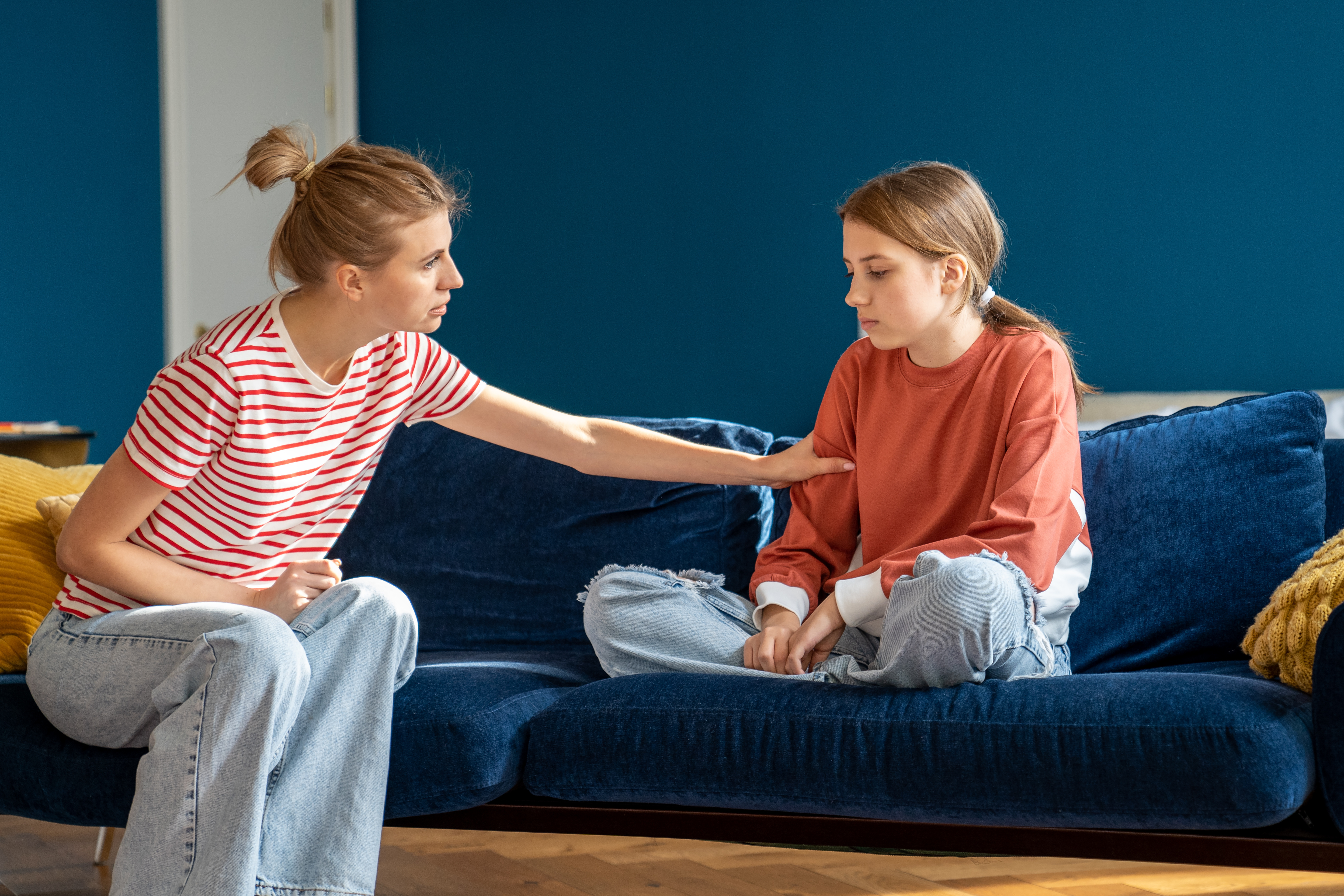 mom sitting with hand on teen daughters shoulder comforting her in distress mental health behavioral suicide parenting hard conversations