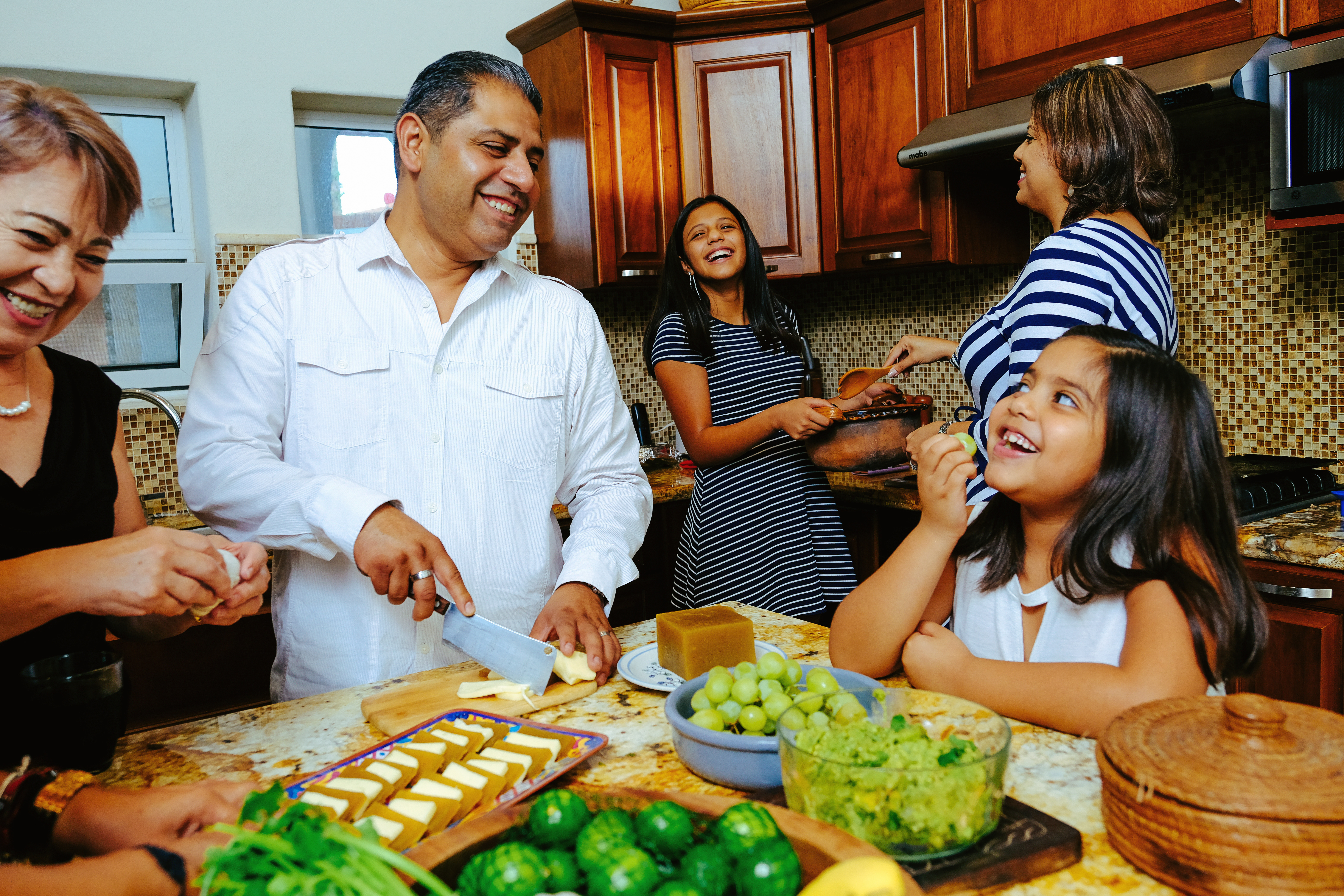 hispanic latino family cooking a meal together standing at the table kids parents grandparents