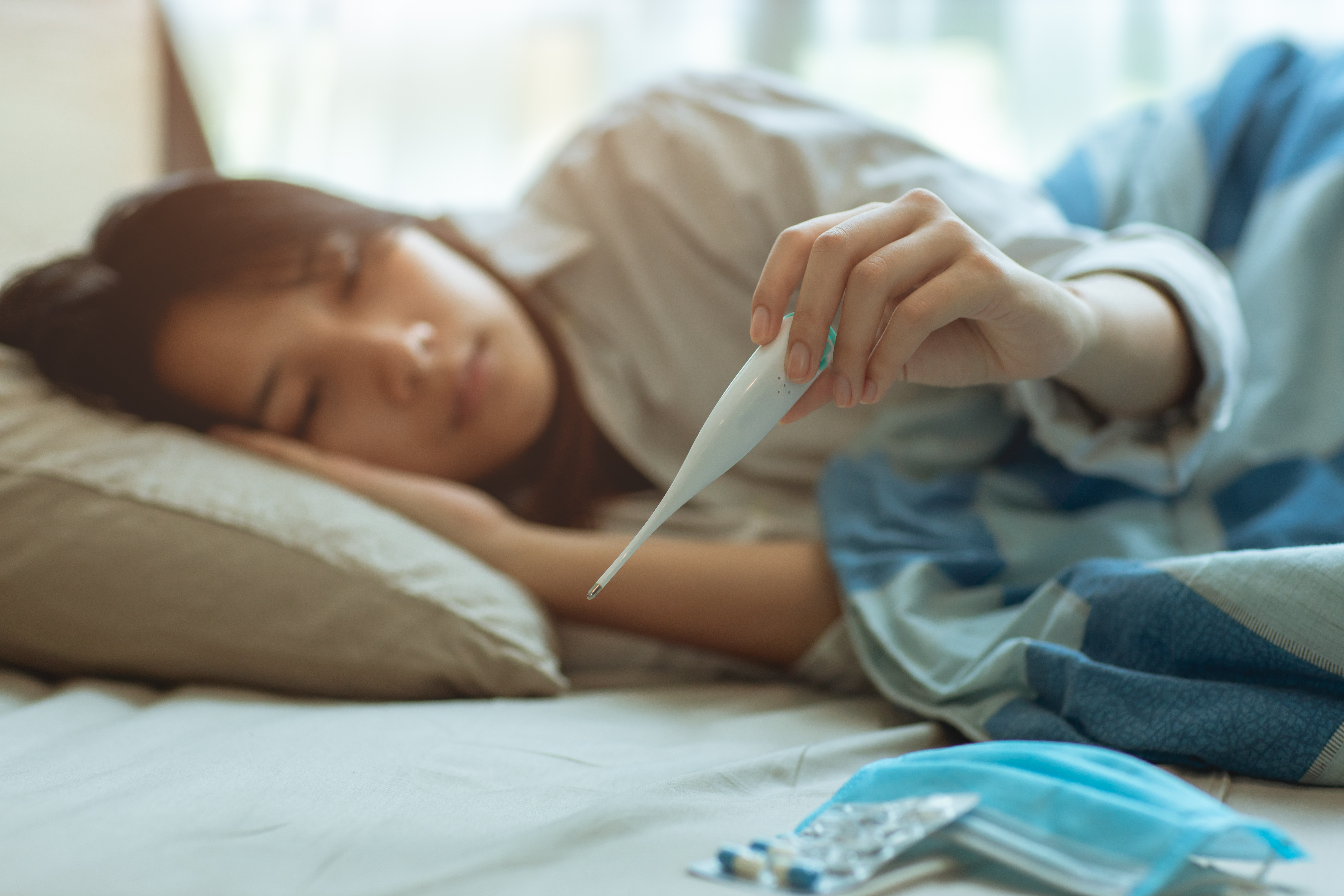 sick teen in bed with thermometer fever illness mask Mononucleosis mono