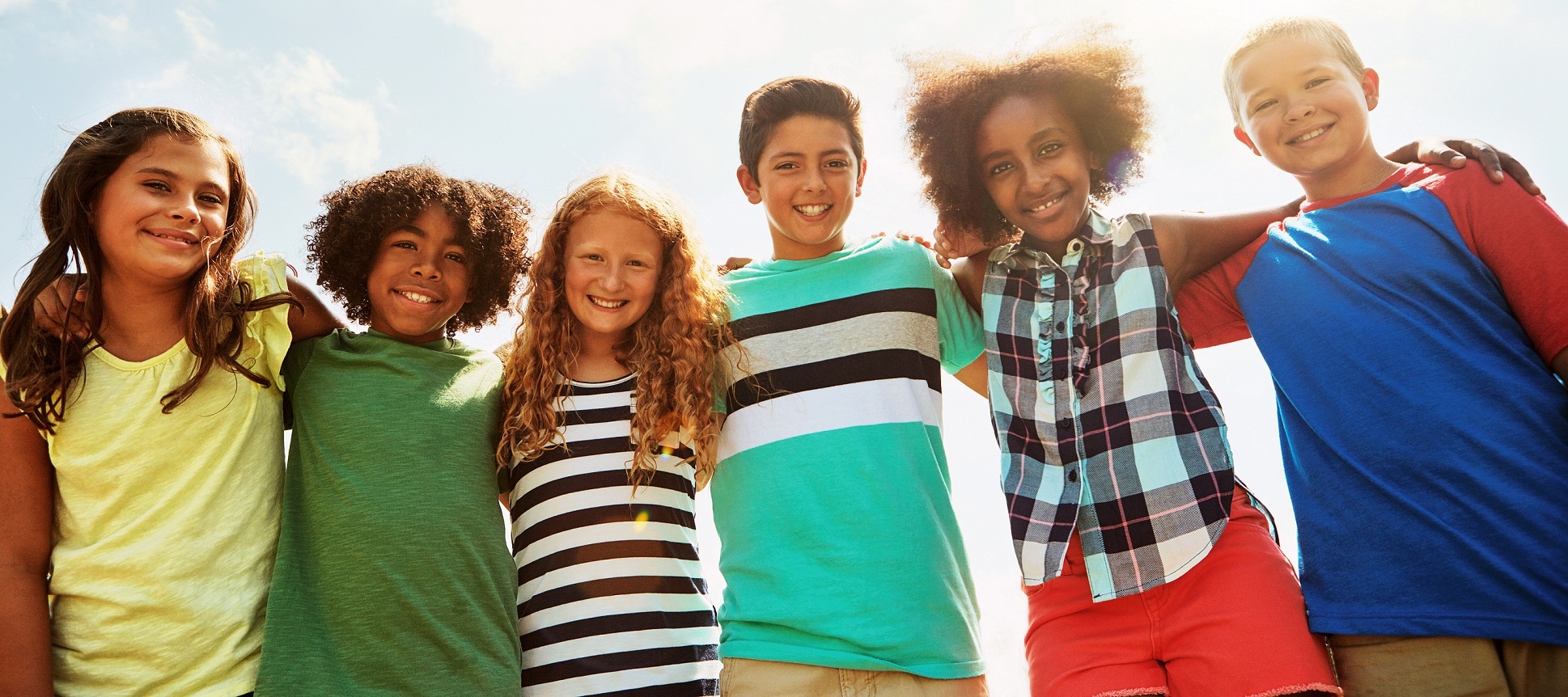 diverse kids smiling with arms around each other image