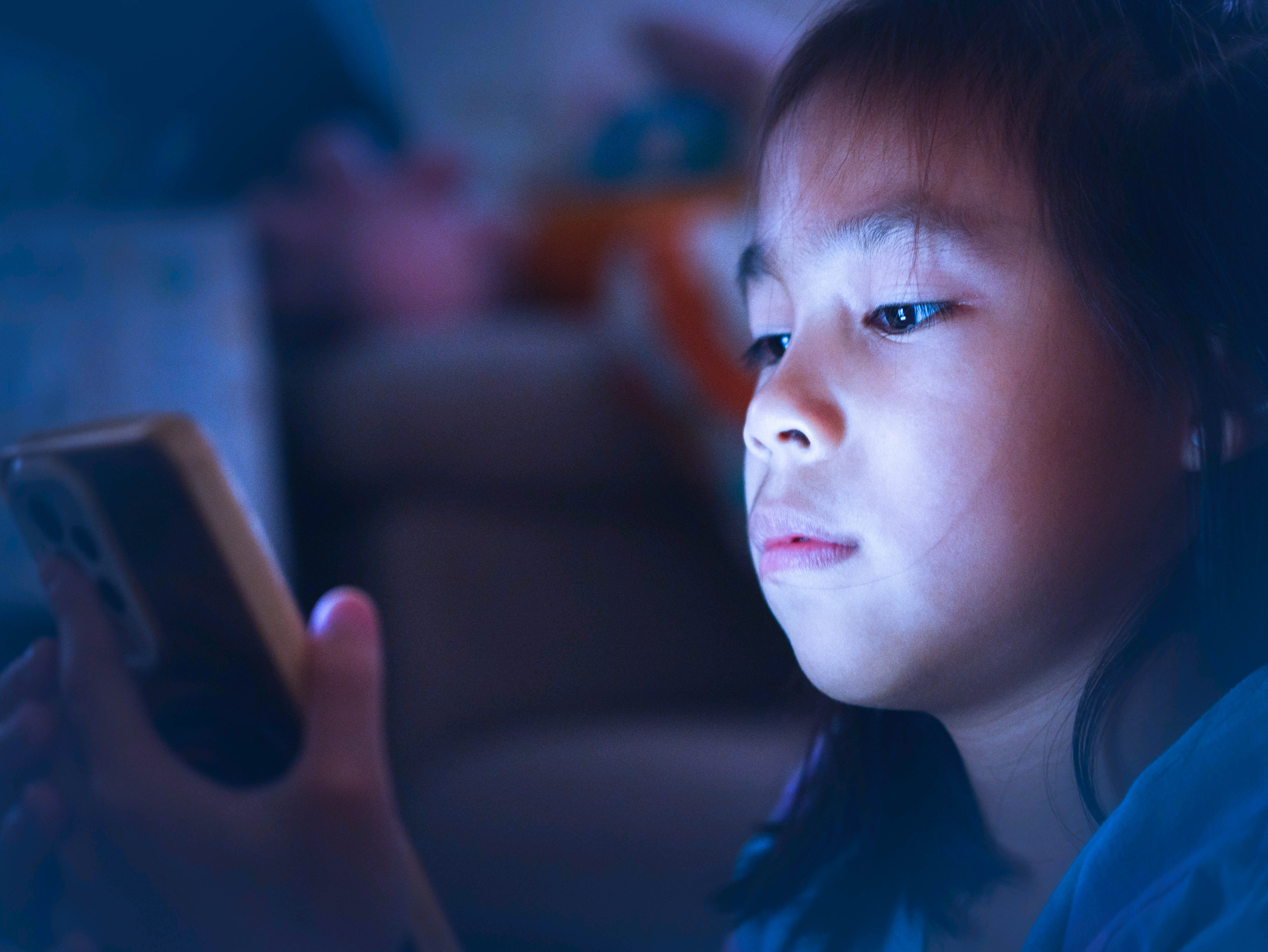 child watching phone in dark blue light screen sleep habits