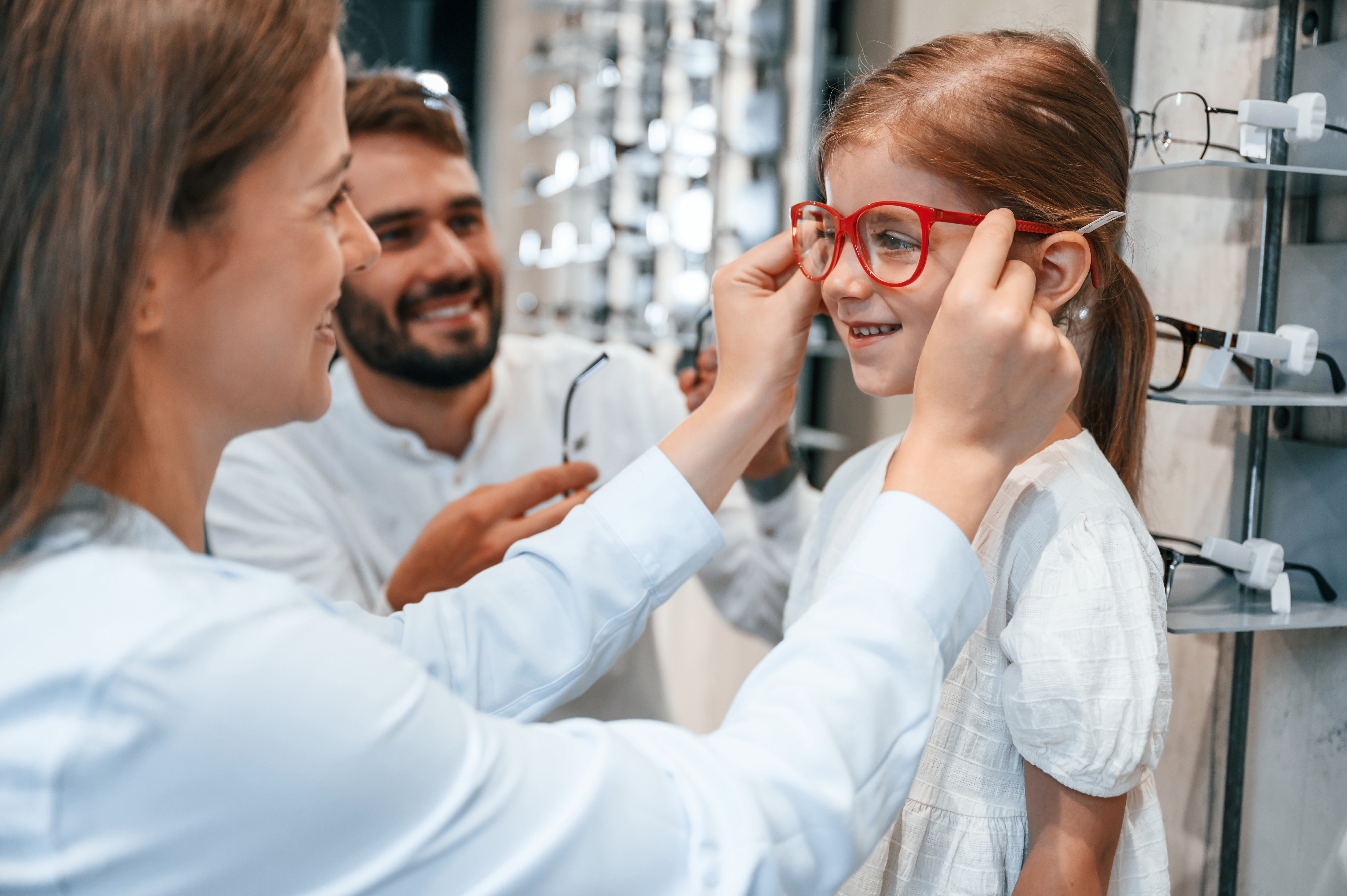 girl trying on glasses in shop with parents smiling healthy eyes eyesight vision