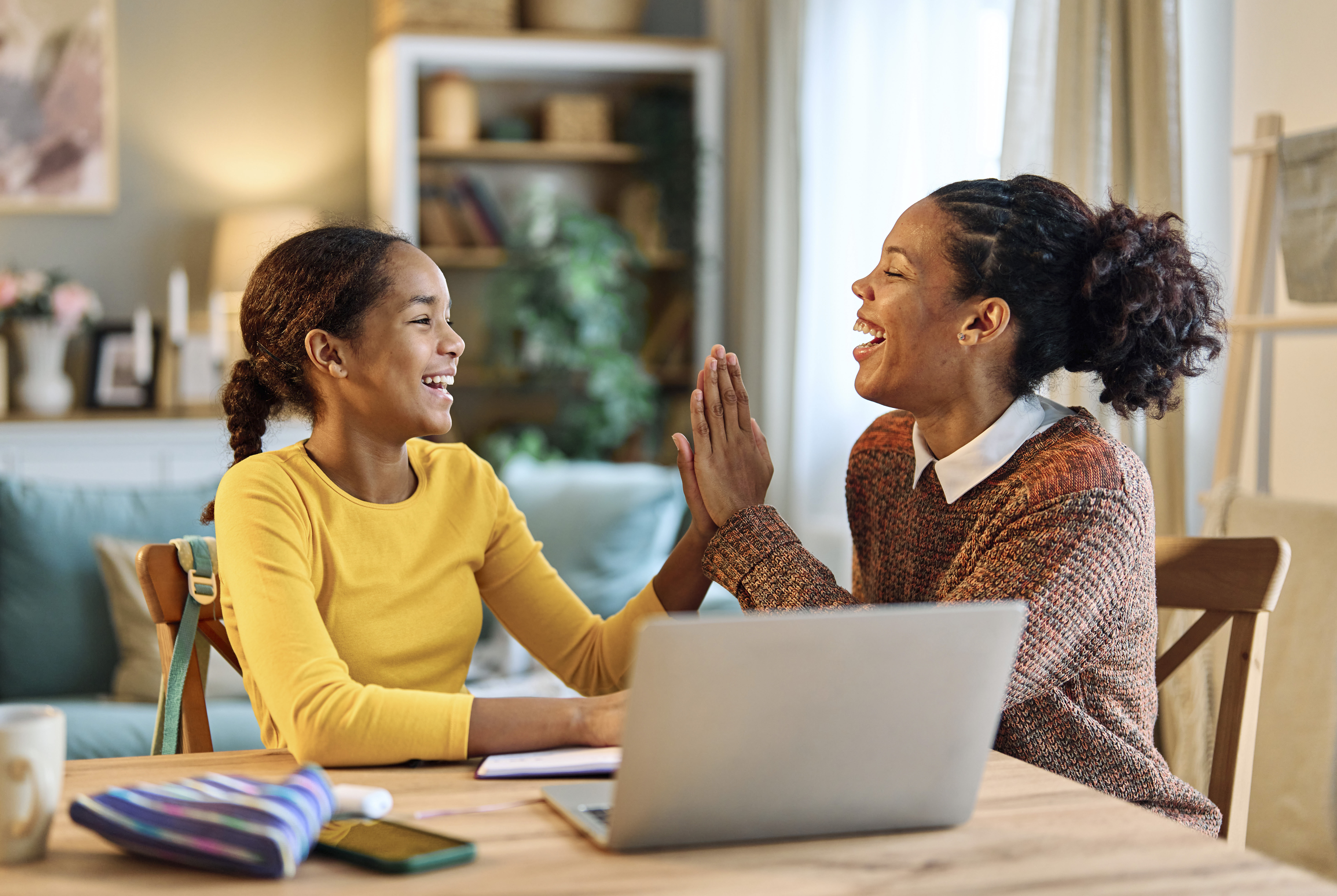 mom and daughter high fiving at computer planning week Sunday reset prep parenting mental health
